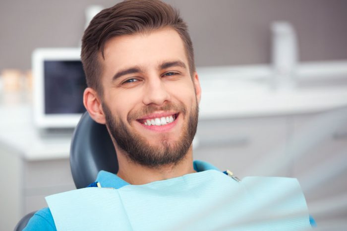 A Male Patient Sitting On A Dental Chair While Having A Smile On His Face