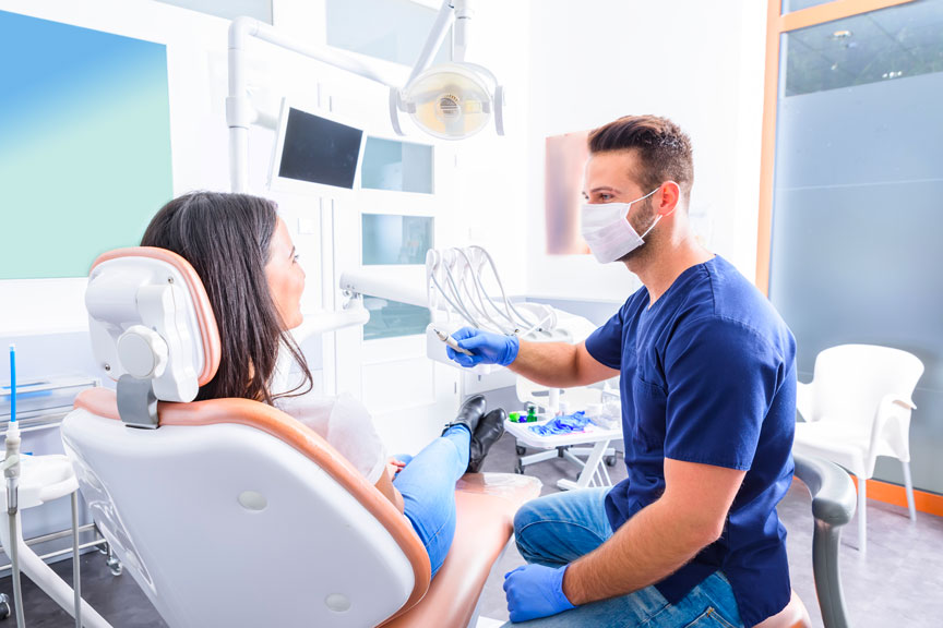 A Young Male Dentist Treating a Female Patient in a Dental Chair